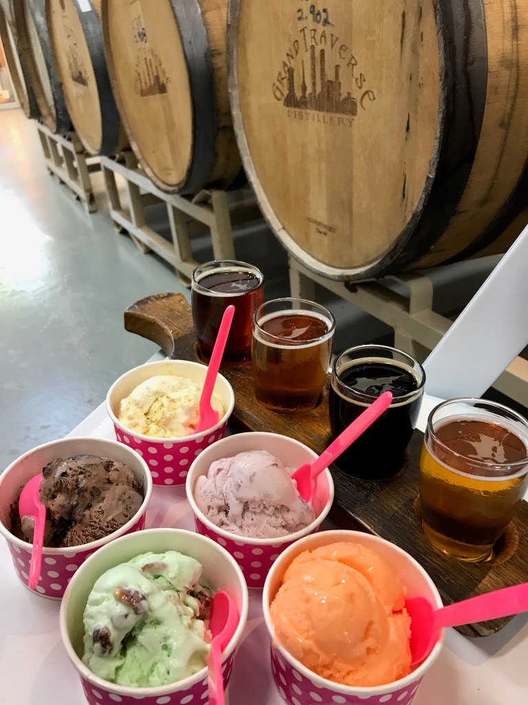 A photo of a beer flight and 5 different bowls of ice cream in a beer barrel cellar.